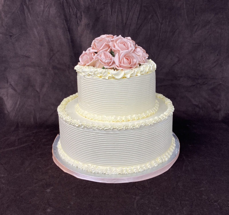 wed 1 1 scaled <p style="text-align: center;">Two tier wedding cake with a combed design and antique pink flowers</p>